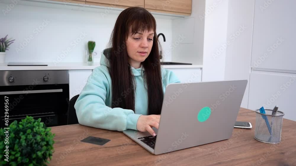 Female freelancer in blue hoodie using a laptop for remote job. Working at home Female freelancer in blue hoodie using a laptop for remote job. Working at home