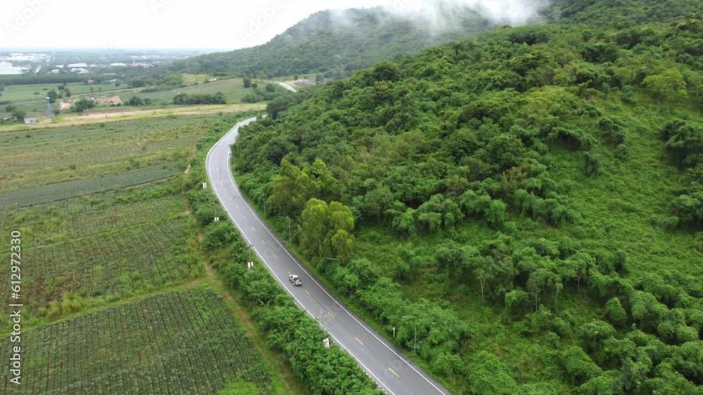 The main road in the countryside that borders the mountain ranges and rural agricultural areas. The beautiful nature of the tropical forest in Thailand. High angle shot taken from a drone. 4K Video The main road in the countryside that borders the mountain ranges and rural agricultural areas. The beautiful nature of the tropical forest in Thailand. High angle shot taken from a drone. 4K Video