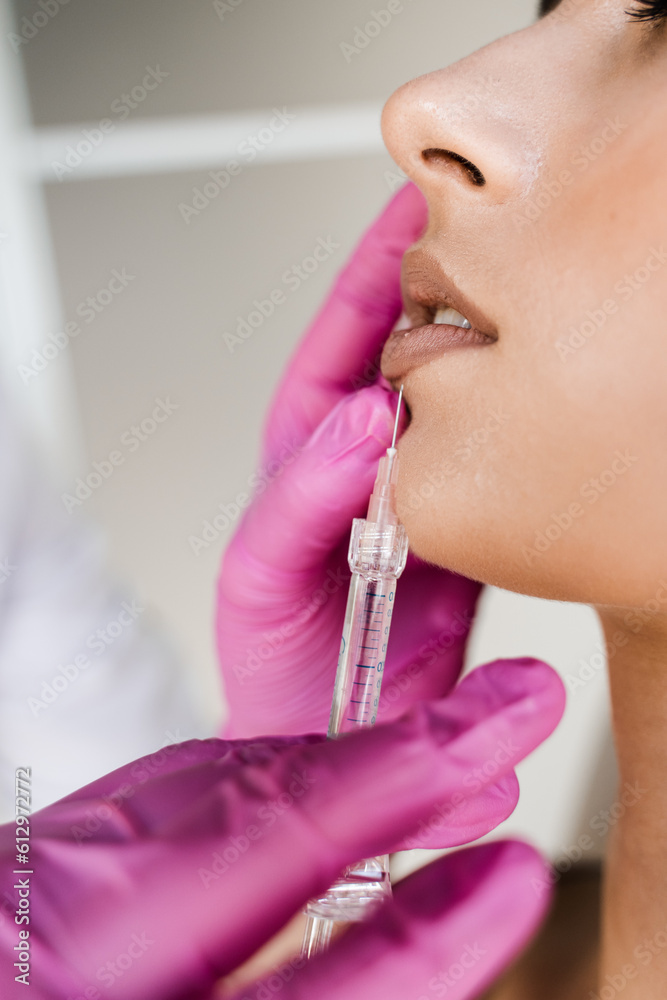 Close-up lips augmentation injections in lips for attractive girl. Cosmetologist injecting hyaluronic acid in lips for augmentation in medical clinic. Cosmetic rejuvenating facial treatment. Close-up lips augmentation injections in lips for attractive girl. Cosmetologist injecting hyaluronic acid in lips for augmentation in medical clinic. Cosmetic rejuvenating facial treatment.