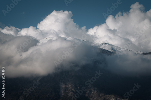Snowcapped mountain top against blue sky and clouds
