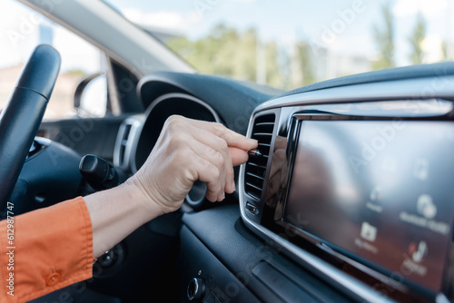 Close-up hand of a woman driver adjusting car conditioner temperature