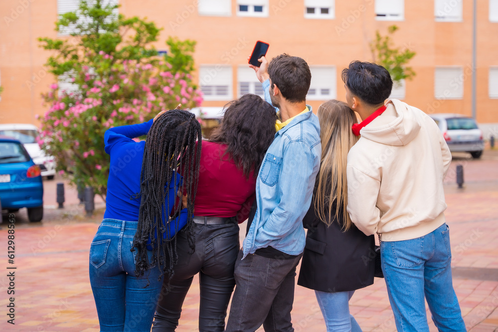 Fototapeta premium Group of multi ethnic friends walking through the university campus having fun taking a selfie, young millennials mobile phone technology concept