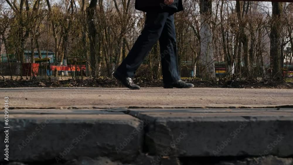 A man in a raincoat walks thoughtfully through the park and sits on a bench A man in a raincoat walks thoughtfully through the park and sits on a bench