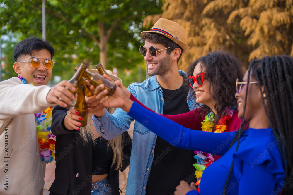 Group of multi ethnic friends at a party in a park having fun - Diverse young people toasting with glass bottles of beer at a summer party, youth concept