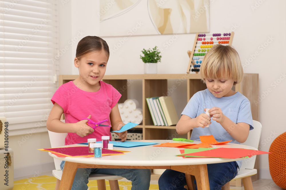 Girl with scissors and boy using glue stick at desk in room. Home workplace Girl with scissors and boy using glue stick at desk in room. Home workplace
