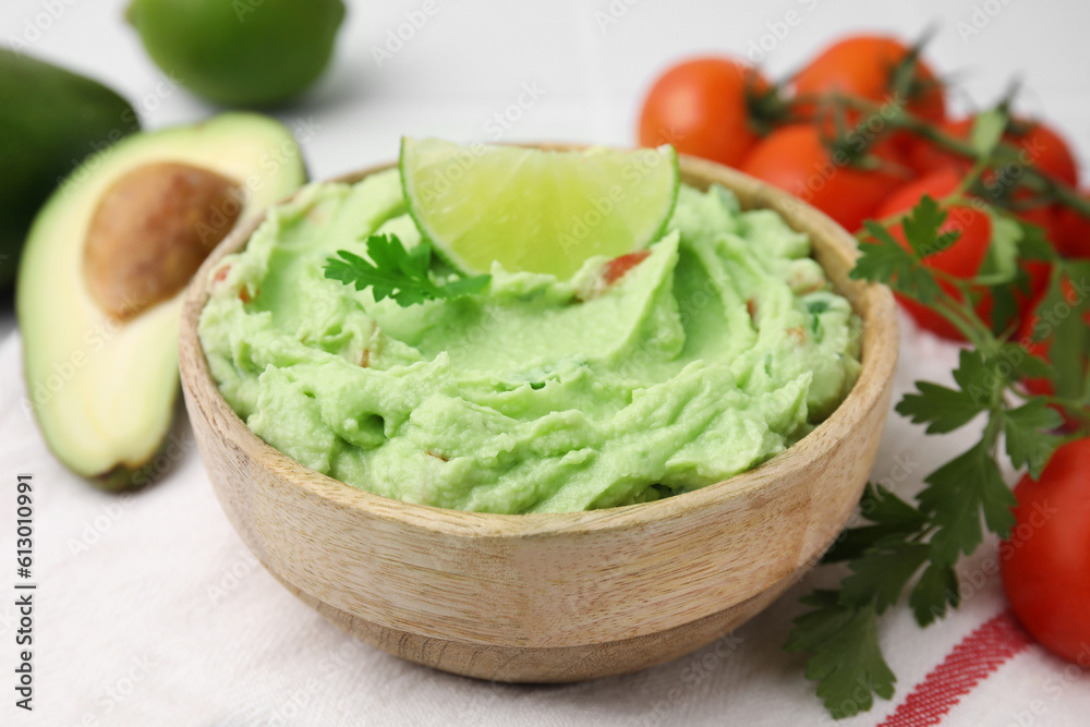Bowl of delicious guacamole and ingredients on table, closeup Bowl of delicious guacamole and ingredients on table, closeup