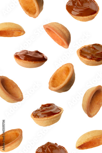 Many empty and filled with caramelized condensed milk nut shell shaped cookie parts falling on white background