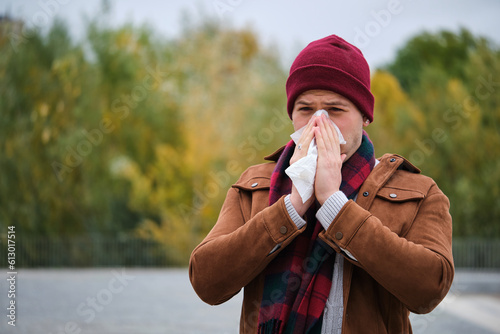 Latin young man blowing nose into tissue during winter. Flu. photo