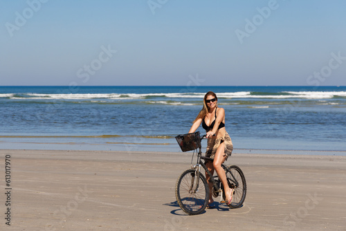 mulher bonita com mais de 40 anos passeando de bicicleta na linda praia de Itaguaré e Guaratuba. Mulher praticando atividade fisica na praia vazia. photo