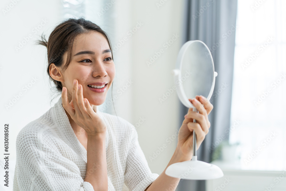 Asian beautiful woman looking at the mirror after apply lotion on face. Asian beautiful woman looking at the mirror after apply lotion on face.