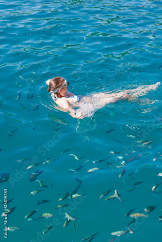 mulher mergulhando nas águas claras do mar cercada de peixes