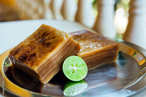Bebinka on iron platter, blurred background, close-up. Bibik, bibinka the national Goan pie, cut into slices. Multi-layer sweet pudding based on coconut milk and flour