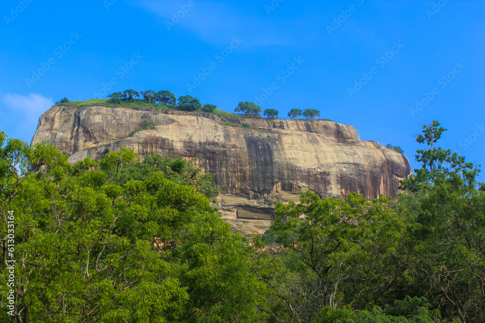Close-up view of Sigiriya Lion Rock fortress behind the trees from Pidurangala Rock, Sri Lanka.