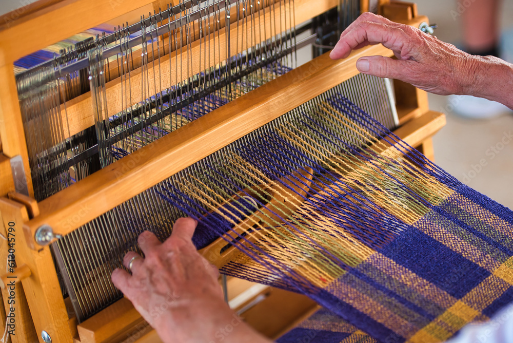 A weavers hands making cloth on a small loom.