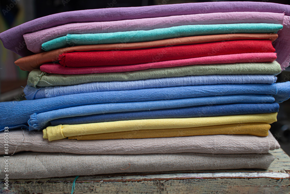 stack pile of colorful textile fabric cloth material made from linen and cotton on a wooden table