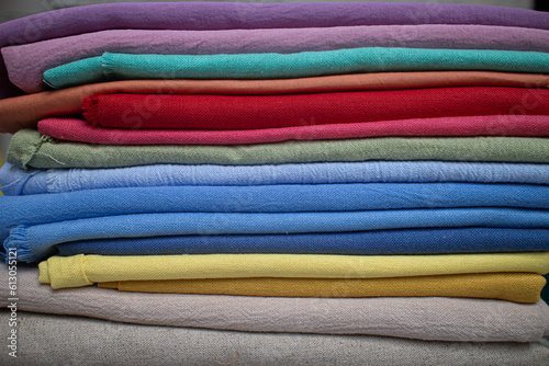 stack pile of colorful textile fabric cloth material made from linen and cotton on a wooden table