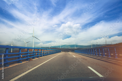Fototapeta Naklejka Na Ścianę i Meble -  View of the bridge over the river through the windscreen. Beautiful landscape with highway, bridge and wind generators. Asturias, Spain
