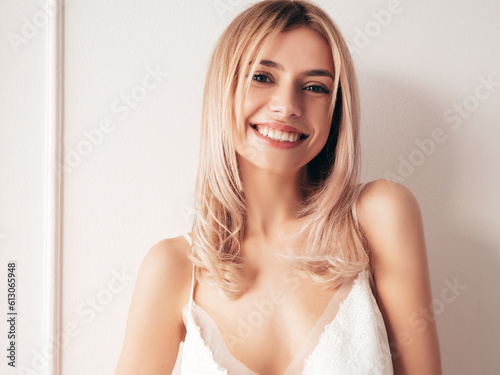 Young beautiful smiling blond female in trendy nightdress clothes. Sexy carefree woman posing in light white studio interior. Positive model having fun after waking up. Cheerful and happy