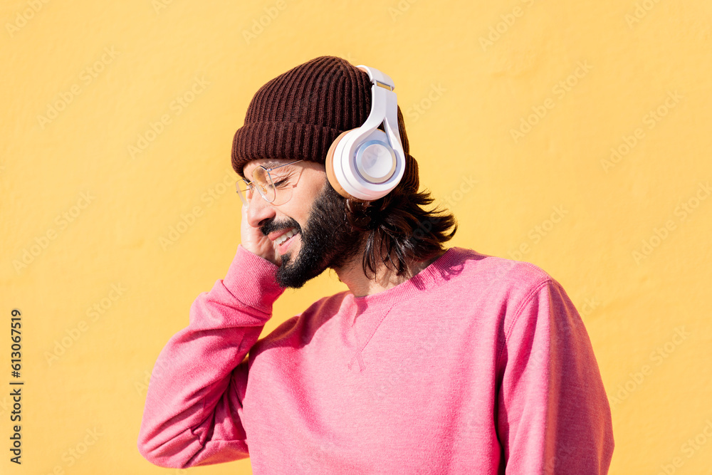 Φωτογραφία young man enjoying happy the music in his headphones with a yellow wall in the b