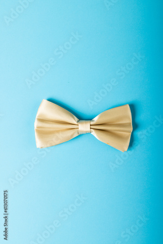 Overhead view of white bowtie isolated against blue background, copy space