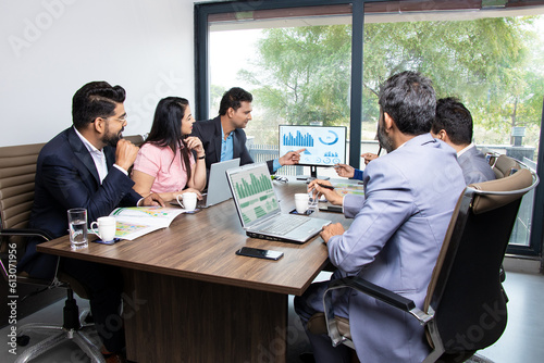 Indian business people meeting presentation in office conference room showing Charts Infographics on TV screen to show growth of company and big data analysis. E-Commerce e-Business.