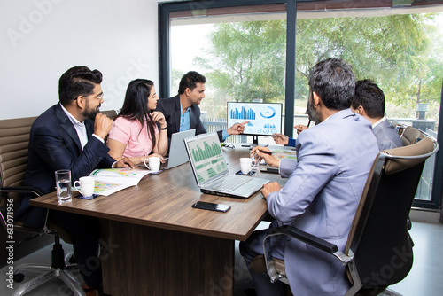 Indian business people meeting presentation in office conference room showing Charts Infographics on TV screen to show growth of company and big data analysis. E-Commerce e-Business.