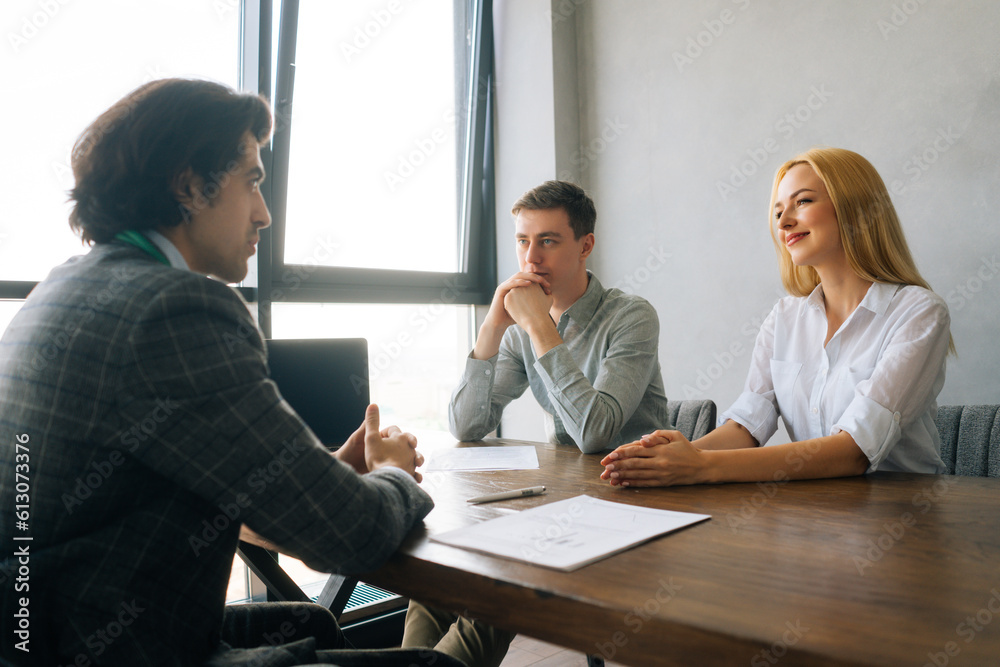 Rear view of boss explaining project strategy to executive manager in modern office meeting. Colleague listen to speaker. Young man sitting at table with laptop. Concept of office life. Rear view of boss explaining project strategy to executive manager in modern office meeting. Colleague listen to speaker. Young man sitting at table with laptop. Concept of office life.