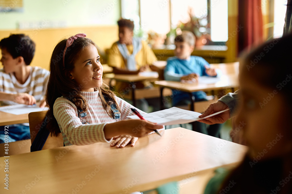 Obraz premium Happy schoolgirl receives test results from her teacher in classroom.
