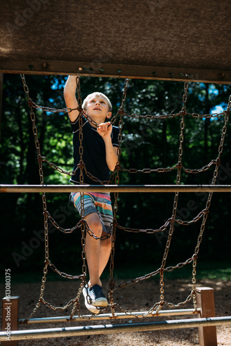 Child climbing on metal playground epuipment at park during summ photo