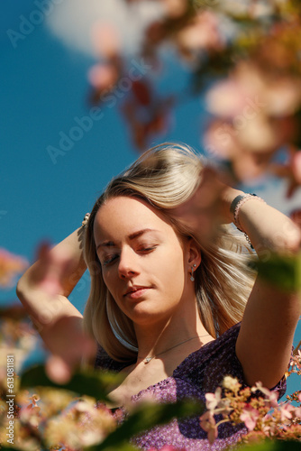 Young blonde woman plays with her hair surrounded by pink flowers photo