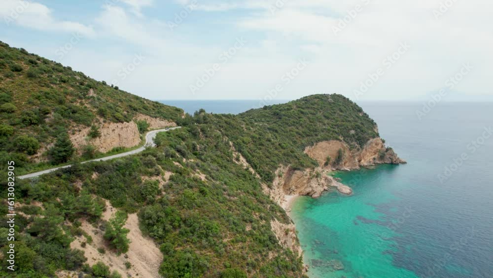 Aerial View Of A Rocky Seaside, Road With A Car Passing By, Turquoise Water, Lush Vegetation, Fari Beach, Thassos Island, Greece Aerial View Of A Rocky Seaside, Road With A Car Passing By, Turquoise Water, Lush Vegetation, Fari Beach, Thassos Island, Greece