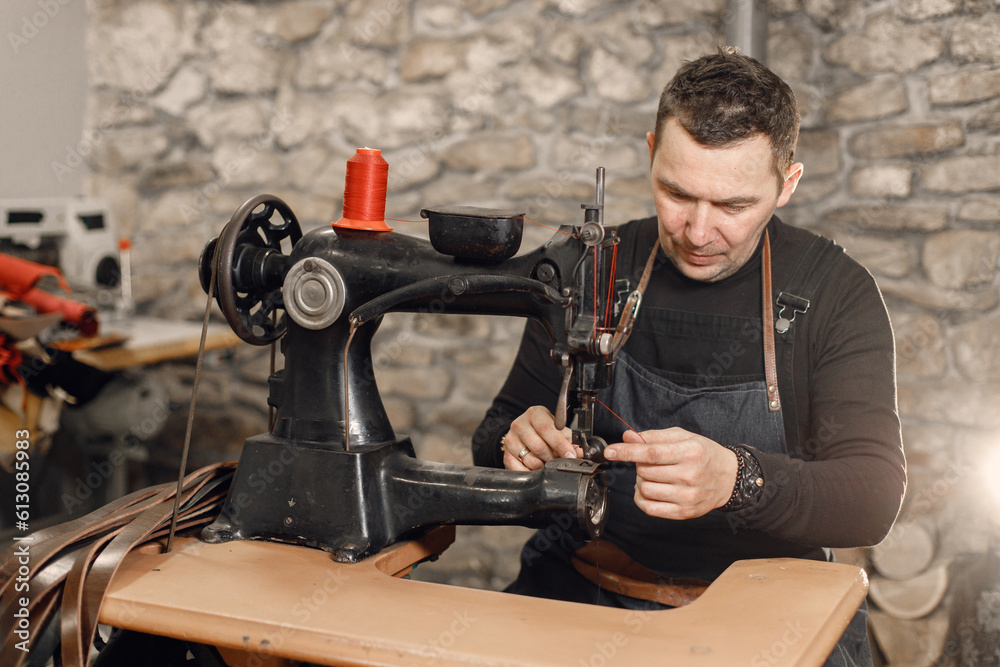 Leather craftsman working on a belt using a sewing machine Leather craftsman working on a belt using a sewing machine