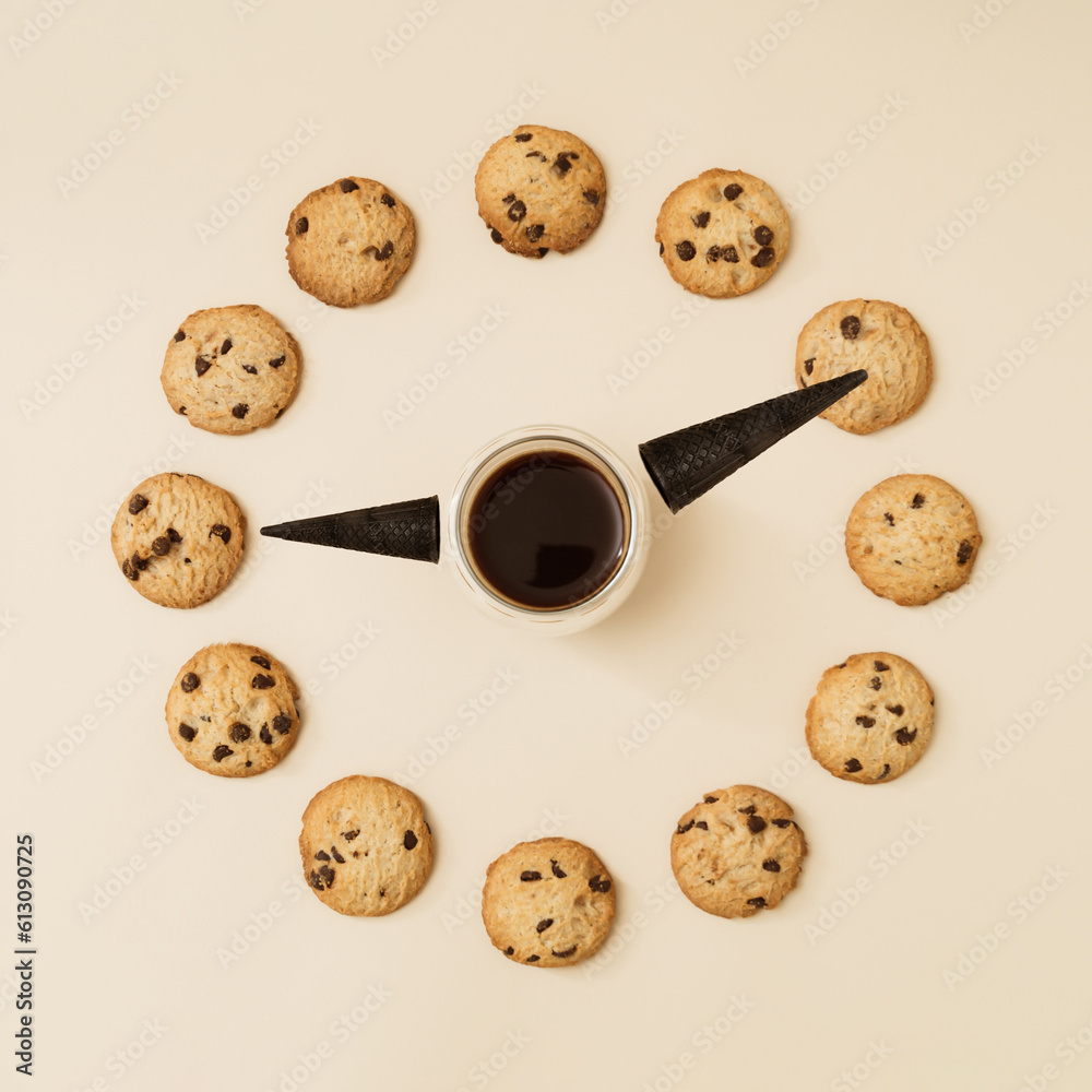 Obraz premium Clock made of cup of coffee, black waffle ice cream cone and chocolate cookies on cream background. Creative food concept. Minimal coffee and biscuits idea. Yummy chip cookies composition. Flat lay.