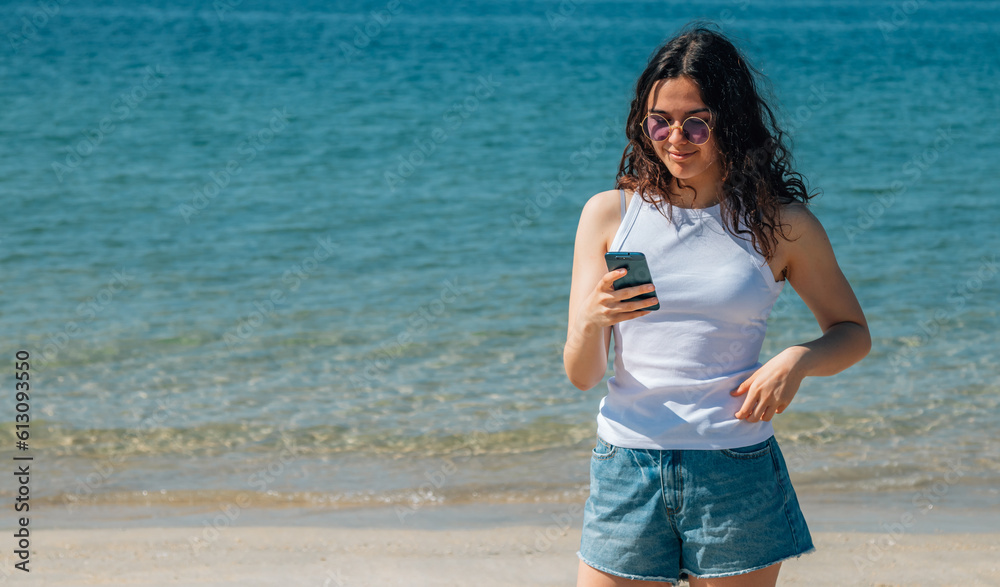 young woman on the beach using mobile phone young woman on the beach using mobile phone