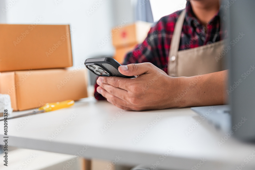 Fototapeta premium Entrepreneurs Small Business SME Independent men work at home Use smartphones and laptops for commercial checking, online marketing, packing boxes, SME sellers, concept, e-commerce team, online sales