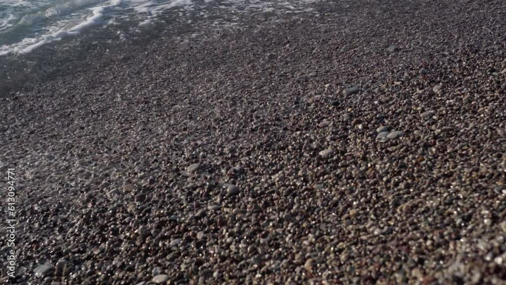 Closeup white foam of blue ocean waves rolling on pebble coast outdoors. Close-up Mediterranean sea water splashing on beach on Cyprus Closeup white foam of blue ocean waves rolling on pebble coast outdoors. Close-up Mediterranean sea water splashing on beach on Cyprus