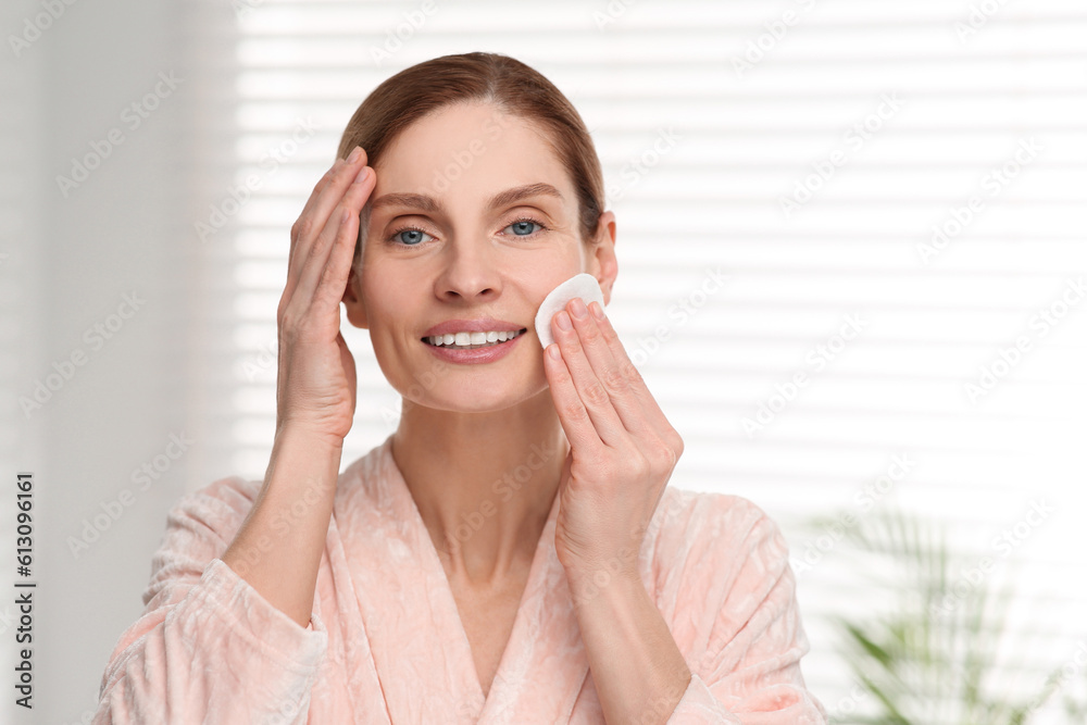 Beautiful woman removing makeup with cotton pad indoors Beautiful woman removing makeup with cotton pad indoors