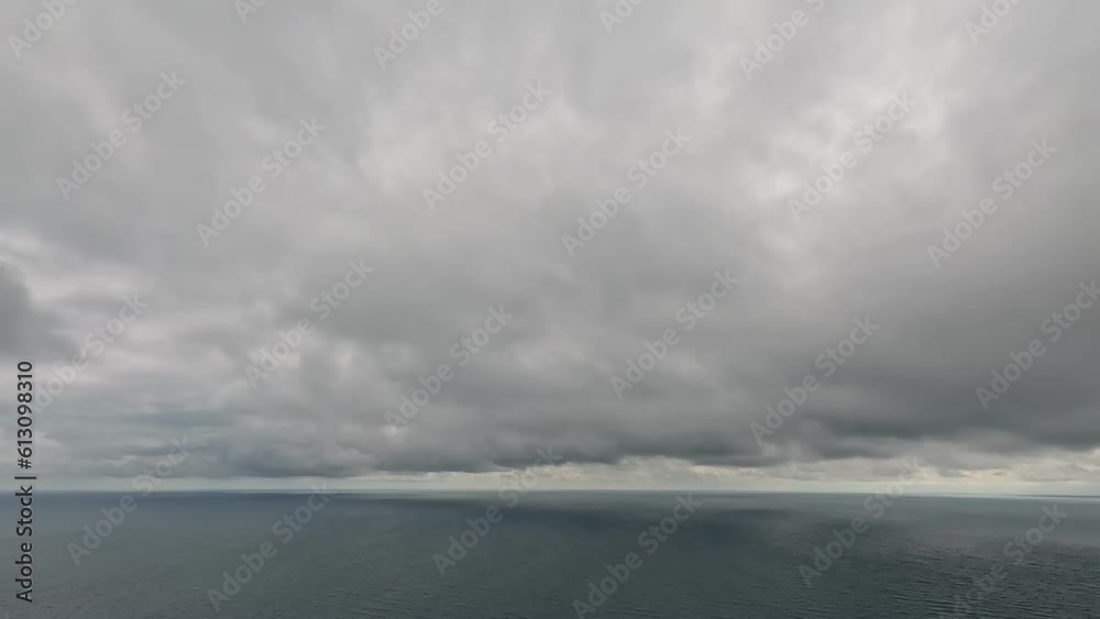 Timelapse of dark rain clouds moving in overcast grey sky over a sea horizon during bad weather. Abstract aerial nature ocean sunset sea and sky. Rainy weather. Climate change, global warming concept Timelapse of dark rain clouds moving in overcast grey sky over a sea horizon during bad weather. Abstract aerial nature ocean sunset sea and sky. Rainy weather. Climate change, global warming concept