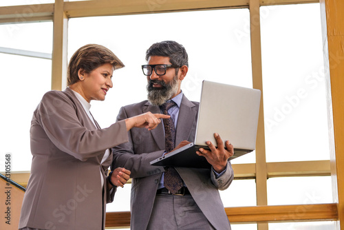 Indian businessman showing some detail to secretary in laptop, boss and secretary in the office discuss new strategies and business development plans