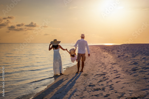 A happy family in walks hand in hand down a paradise beach during sunset tme and Fototapet