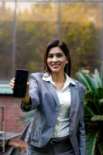 Young indian businesswoman showing smartphone screen
