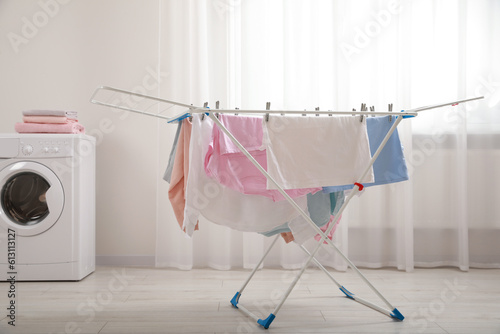 Clean laundry hanging on drying rack indoors
