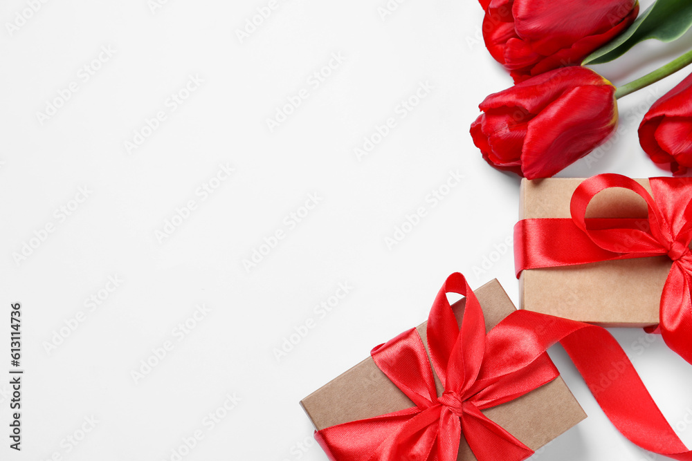 Beautiful gift boxes and red tulip flowers on white background, flat lay. Space for text Beautiful gift boxes and red tulip flowers on white background, flat lay. Space for text