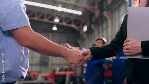 Business man manager leader and woman assistant holding document file and shaking hands after reach an agreement together at metal factory