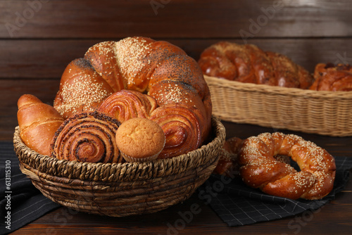 Wicker baskets and different tasty freshly baked pastries on wooden table