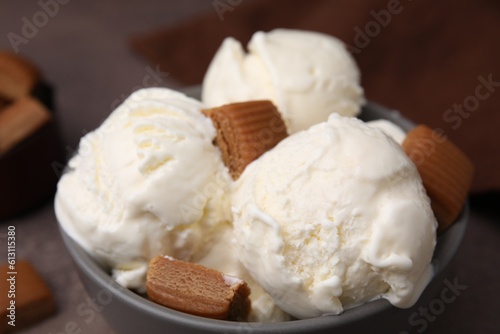 Scoops of ice cream with caramel candies in bowl on table, closeup