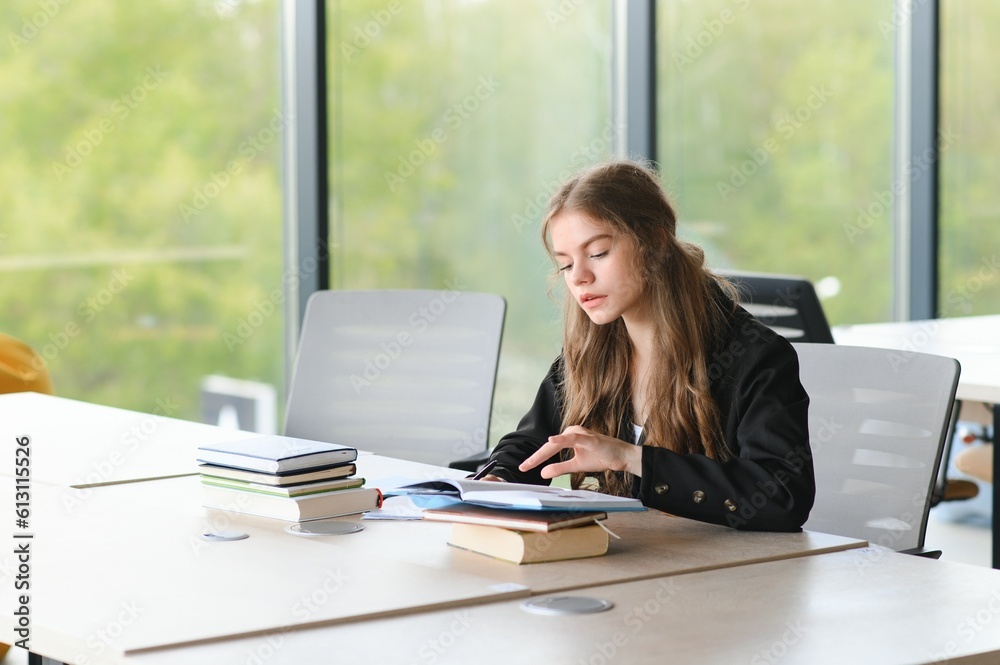 Teen girl studying with textbook writing essay learning in classroom. Teen girl studying with textbook writing essay learning in classroom.