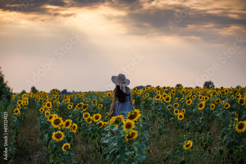 Woman in a field of sunflowers. Sunflowers and emotions. Girl in the field. Person on a field with sunflowers at sunset. View