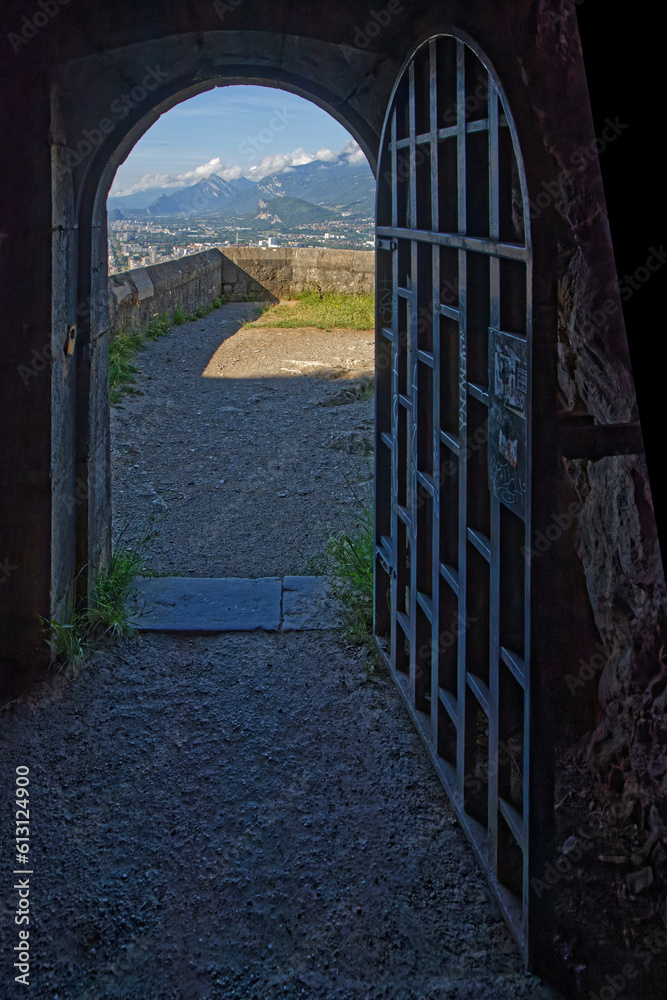Obraz premium GRENOBLE, FRANCE, June 12, 2023 : A door from the fortress of La Bastille, overlooking the city as a frame around the mountains landscape