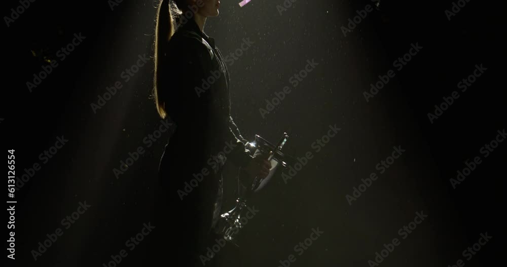 Silhouette of female woman race car driver celebrating the win in a race against bright stadium lights, rising a trophy over her head Silhouette of female woman race car driver celebrating the win in a race against bright stadium lights, rising a trophy over her head